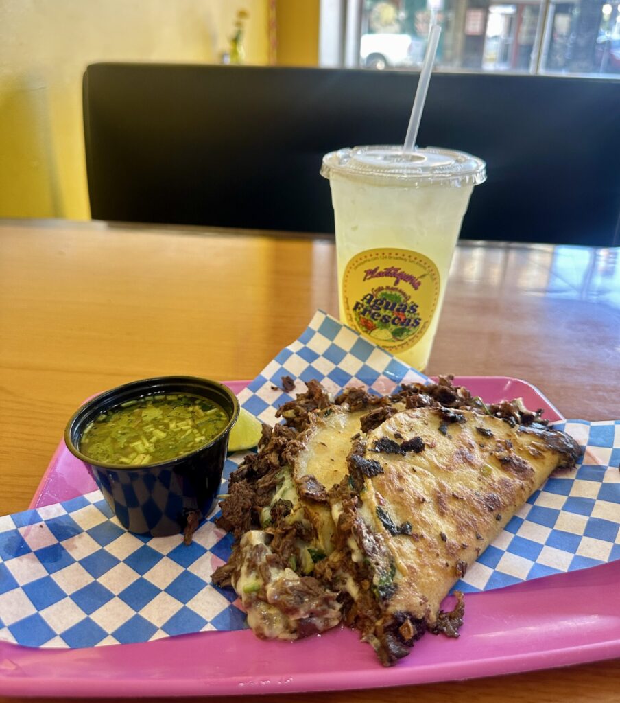 quesadilla with green salsa and drink on a table
