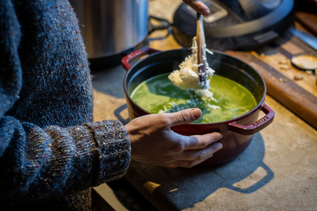 hand adding rice to green soup