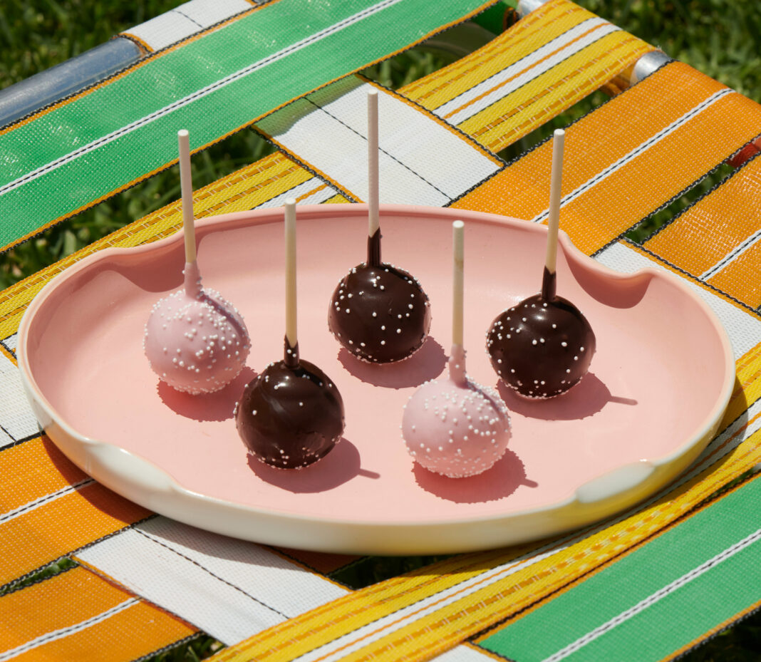 cake pops on a pink plate on a colorful lawn chair