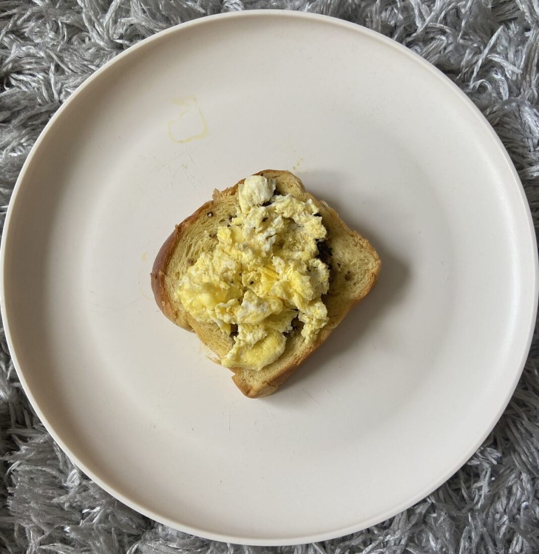 scrambled eggs on a piece of toast on a white plate