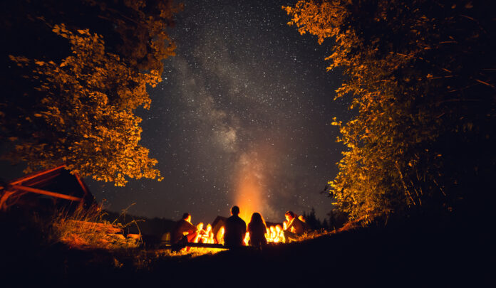 a group of people sitting around a campfire at night