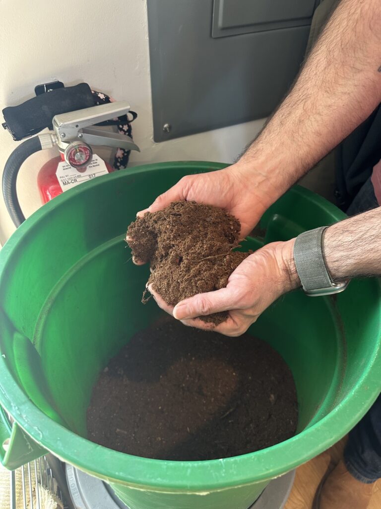 hands holding compost above compost bin
