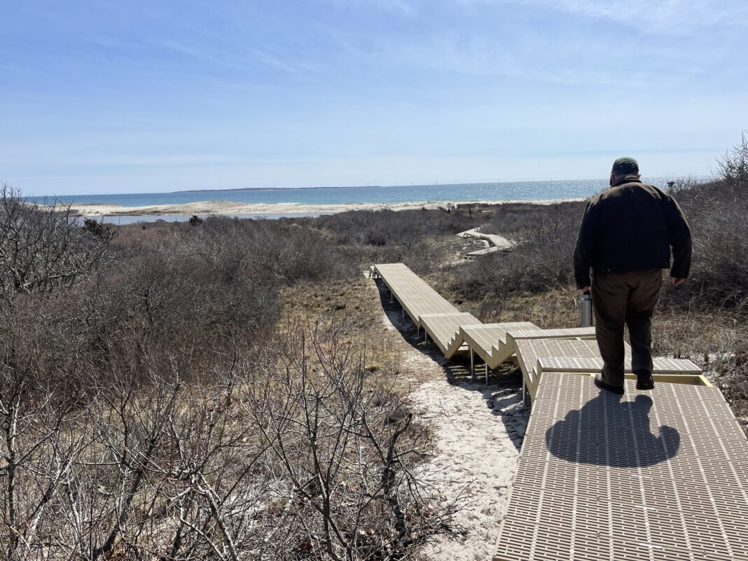 a man walking down a trail leading to the ocean