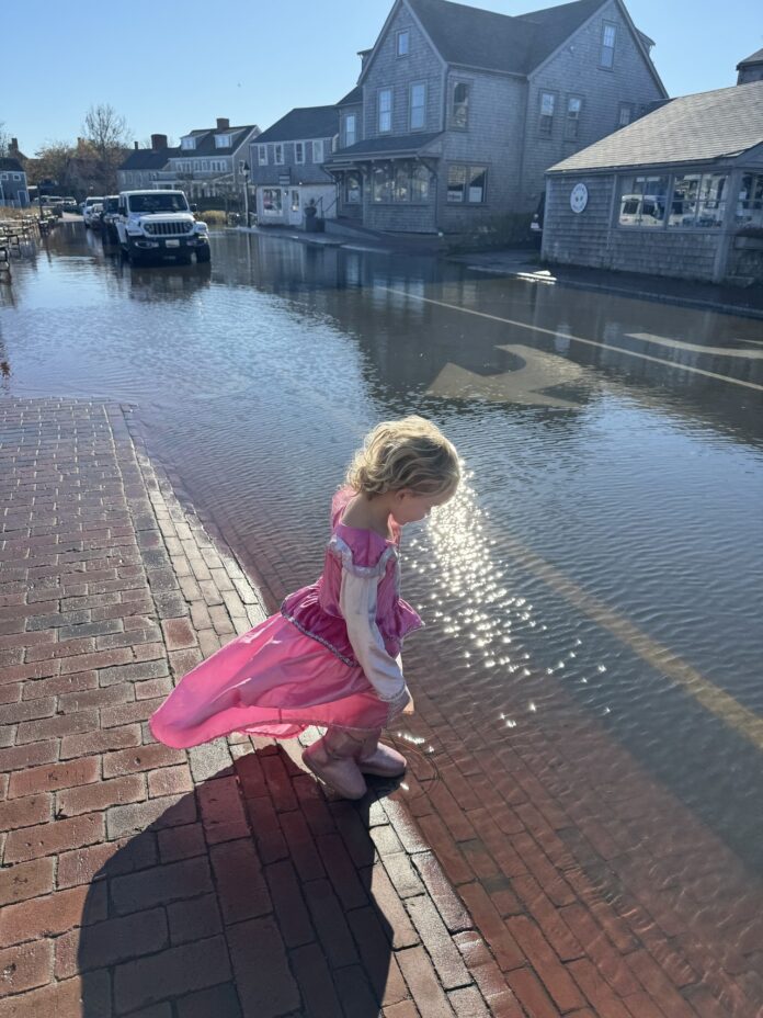 girl wearing pink princess dress stepping in flooded street