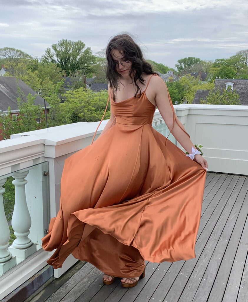 a young woman wearing an orange prom dress that she thrifted