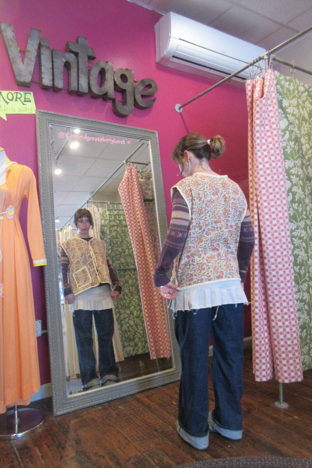 a young woman tries on a vintage vest from raspberry berret