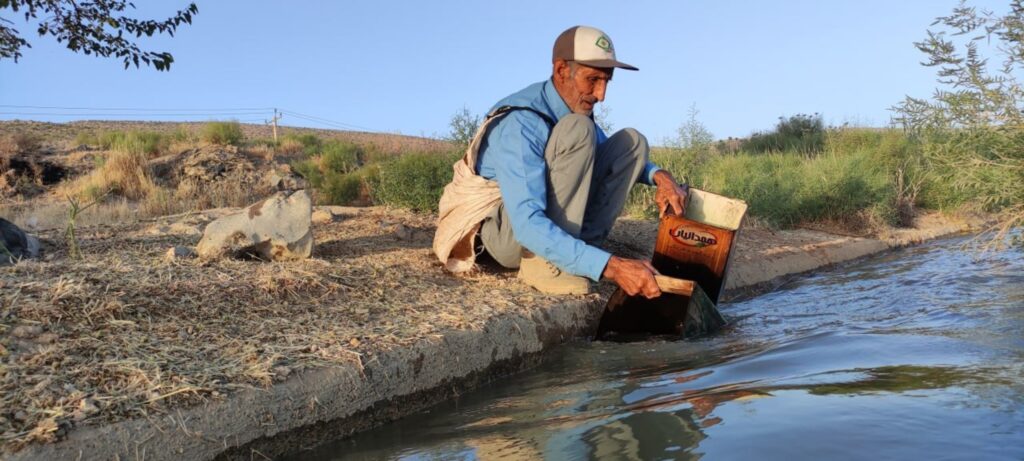 an older Iranian man fills up a container with water