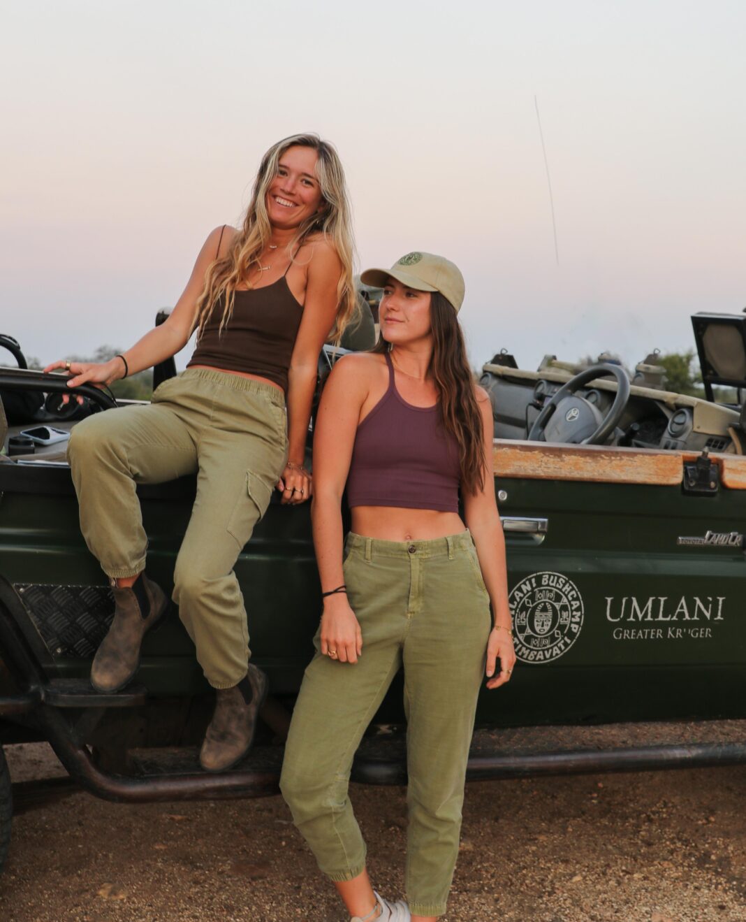 two young woman sitting on a car in the safari