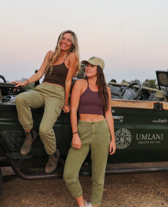 two young woman sitting on a car in the safari