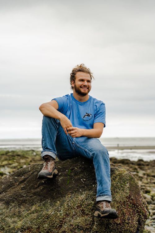 a man sitting on a rock at a beach