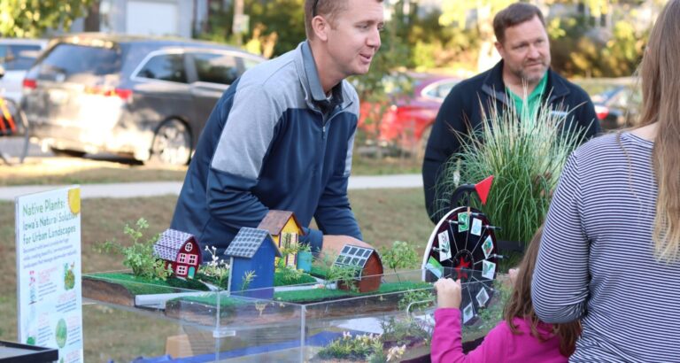 Cameron Agan demonstrates a model of water management practices at an event