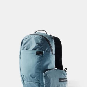 a blue backpack made by matador equipment shown with a little bag in front of fit that the backpack can compress down into.
