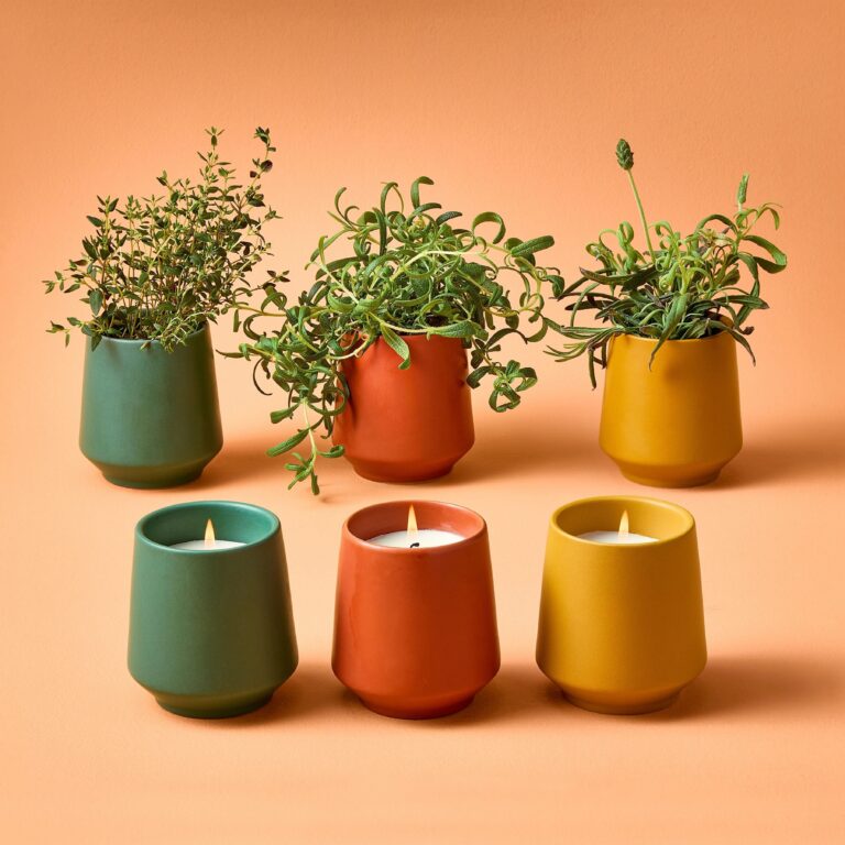 Three clay vessels filled with candles, with three matching clay vessels behind them filled with herbs.