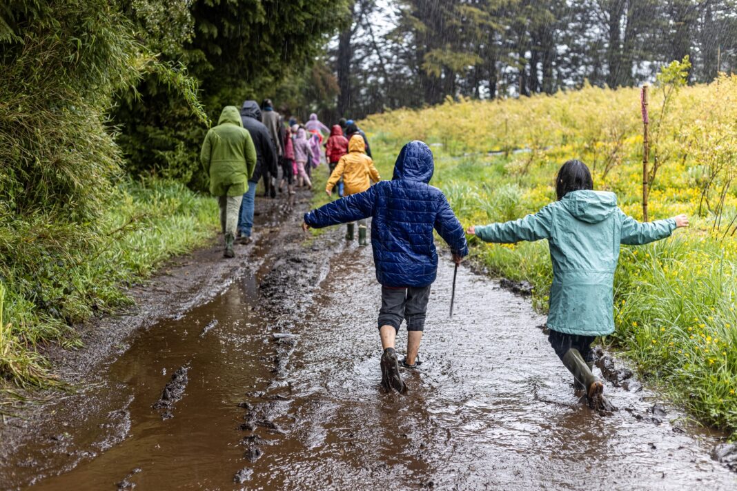 children and adults walking in the rain through the countryside