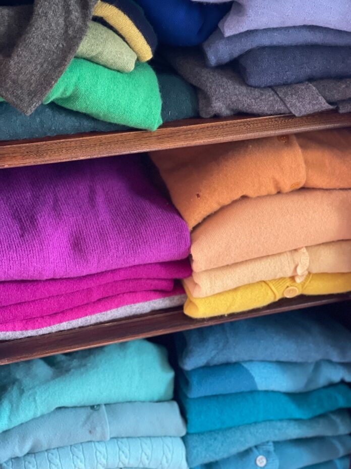 colorful sweaters folded in a closet