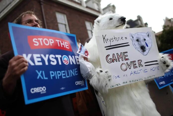protestors holding signs that read "stop the keystone XL pipeline"