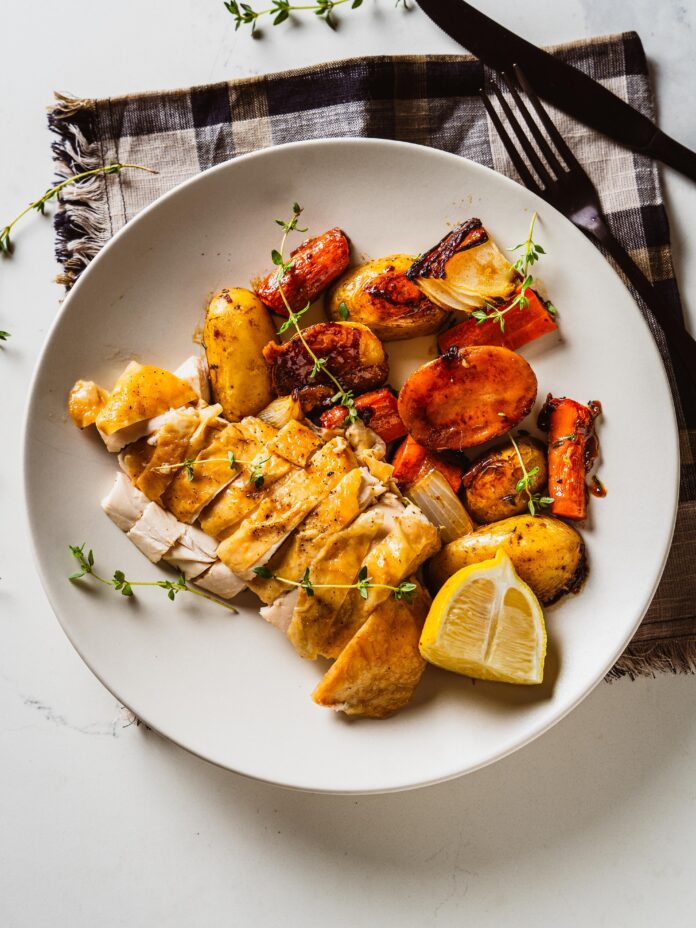 two roast chickens plated with veggies on the side