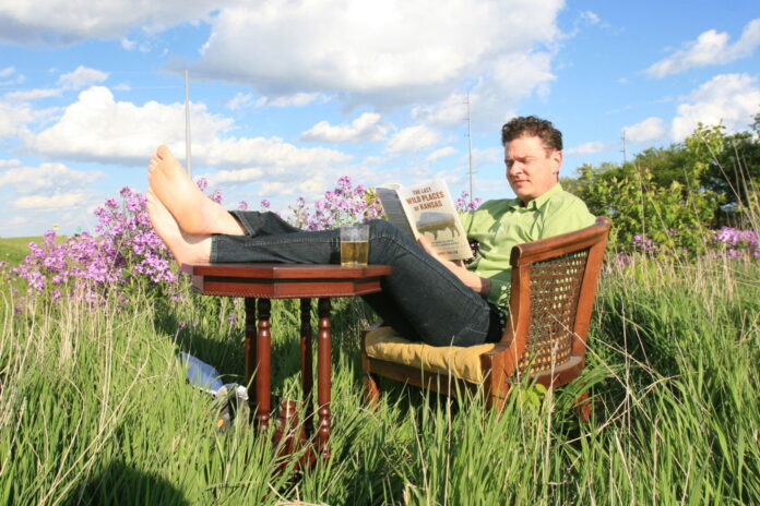 George Frazier reading in a field