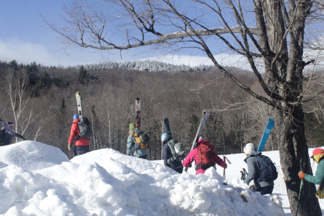 women carrying skis toward a trailhead