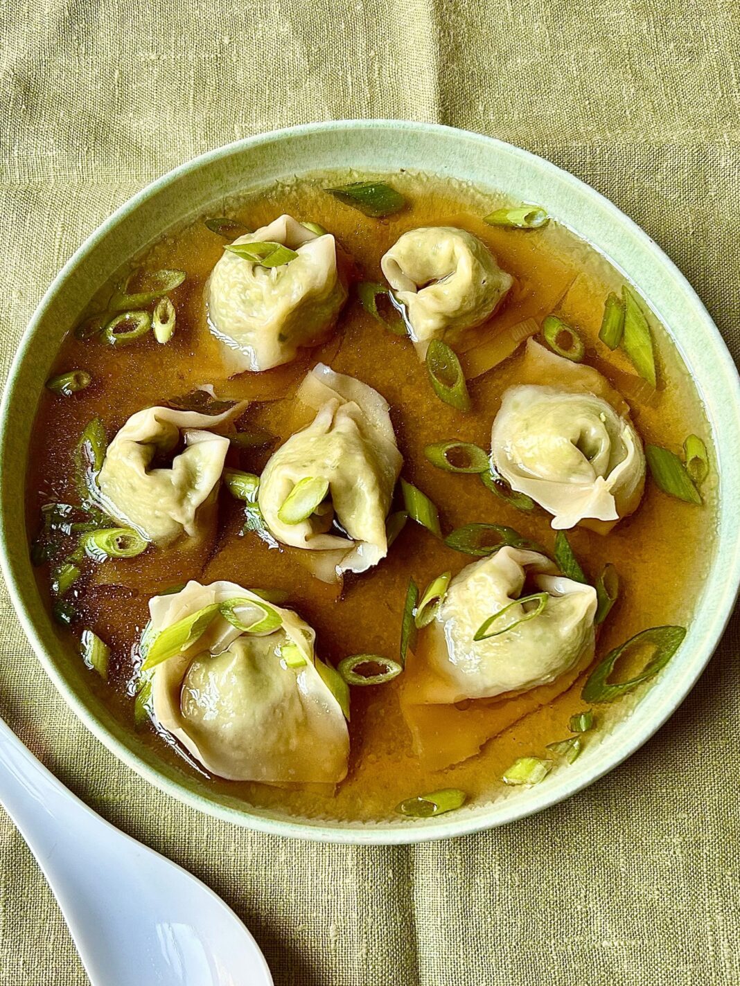 wonton soup topped with tofu, broccoli, and kale served in a bowl
