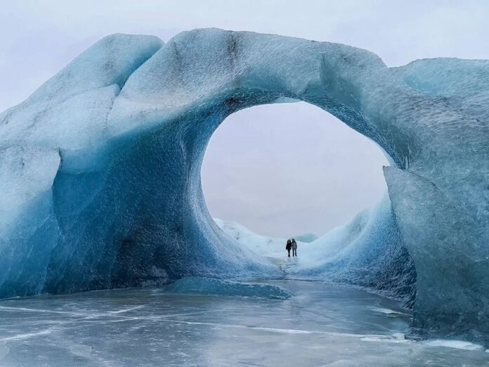 two people stand under an ice cave