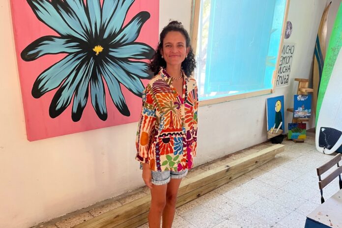 Cristina Munoz Laboy stands in front of her painting of the puerto rican endangered plant species