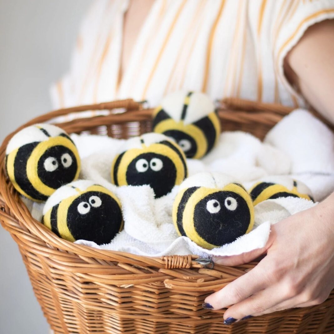 A laundry basket with wool dryer balls in it that look like bees