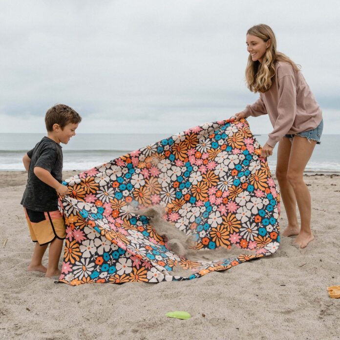 a woman and a child using a floral beach blanket