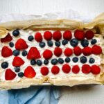 a rectangular cake with white frosting topped with strawberries and blueberries