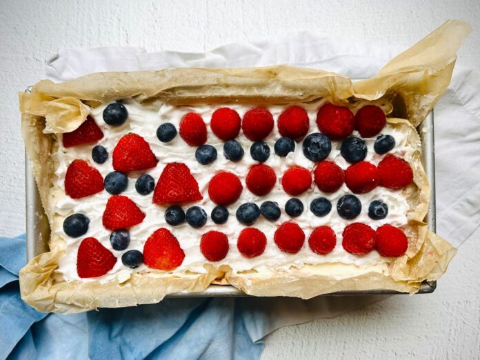 a rectangular cake with white frosting topped with strawberries and blueberries