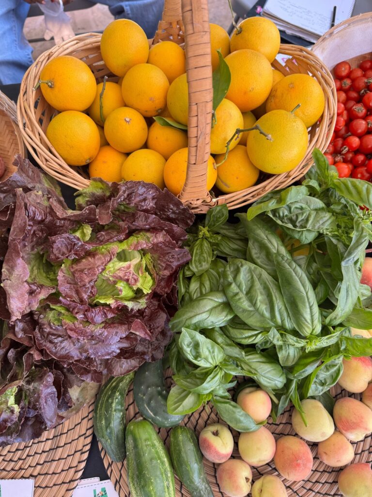 baskets filled with oranges, peaches, and tomatoes