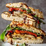a grilled veggie sandwich cut in half on a plate