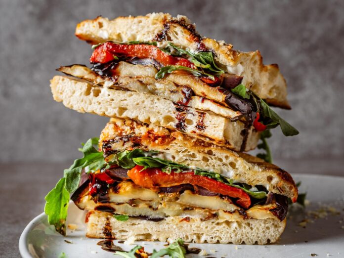 a grilled veggie sandwich cut in half on a plate