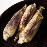 three pieces of corn grilled in the husk