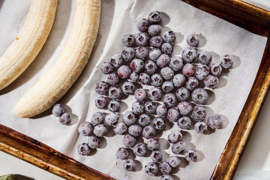 frozen berries and sliced bananas on a sheet pan