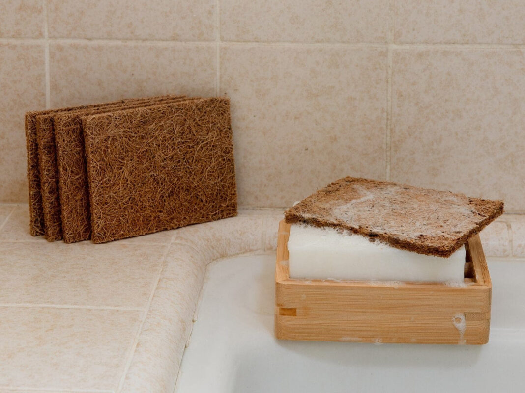 A brown rectangular sponge on top of a block of soap on a kitchen counter.