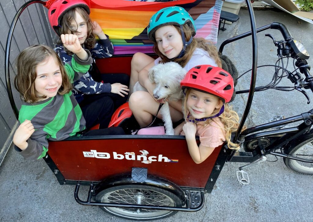 Four kids and a dog in a bike wagon