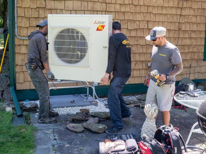 three people installing a heat pump